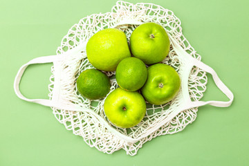 Net bag with green fruits on a green background. Zero waste. Monochrome green.
