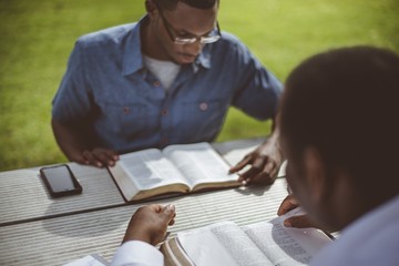 African-American male friends sitting at the table and reading the Bible at the table