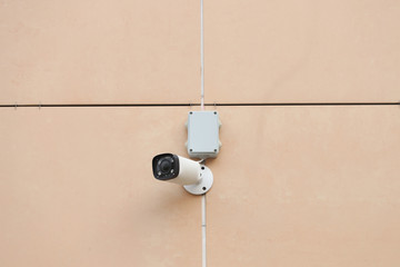 A security camera hangs on the wall of the building