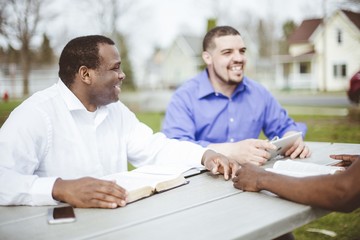 Group of diverse people sitting at the table and reading the Bible
