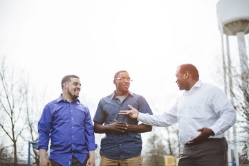 Group of diverse male friends talking to each other and smiling