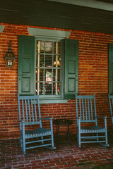 Fototapeta na wymiar Front porch with blue chairs^ green windows and door of old craftsman style home