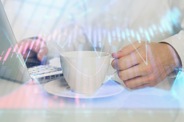 Double exposure of graph with man typing on computer in office on background. Concept of hard work.