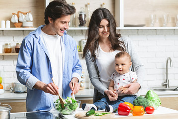 Parents with baby cooking organic healthy lunch at kitchen