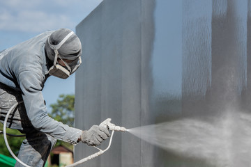 Airless Spray Painting, Worker painting on steel wall surface by airless spray gun for protection rust and corrosion. - obrazy, fototapety, plakaty