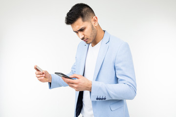 handsome man in a jacket orders purchases via the Internet from a smartphone holding a credit card in his hands