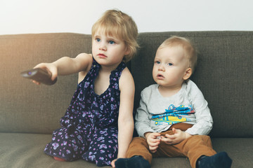 two children sitting in sofa and watching tv at home