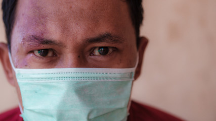 Indonesian man wearing a medical face mask to anticipate the spread of diseases outbreak caused by...