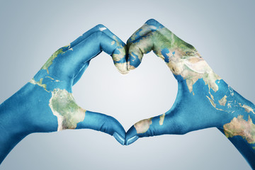 Female hands, painted in the world map,  forming heart shape isolated on blue background - 330497255