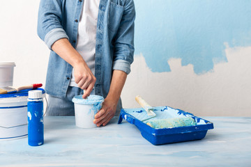 Man in jeans mixes paint in bucket © Prostock-studio