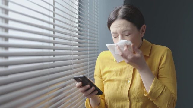 Woman chatting with her phone and sneezing