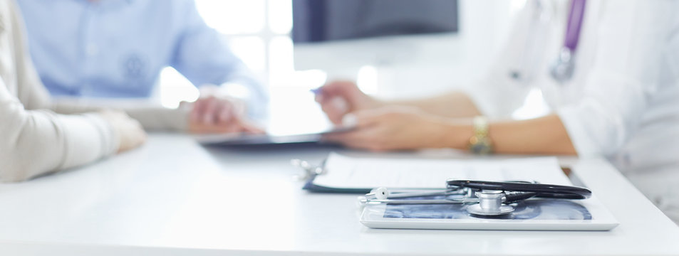 Attentive senior doctor listenint to patient in her office