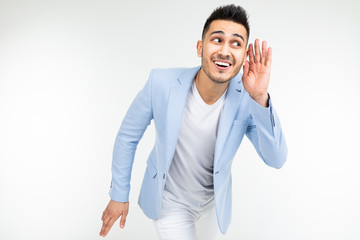 brunette man in a blue jacket listens to the sounds on a white background with copy space