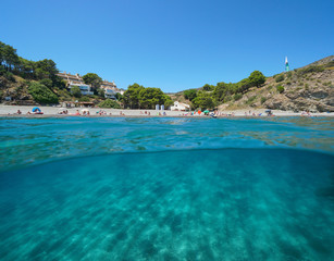 Spain Mediterranean sea, beach coastline in summer vacations with sand underwater, split view over and under water surface, Costa Brava, Colera, Catalonia