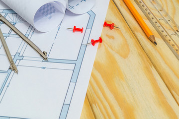Rolled house diagrams and accessories for drawing lying on construction drawing and wooden boards