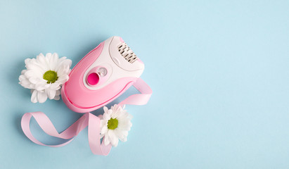 Pink epilator with flowers on  blue background. Depilation concept.