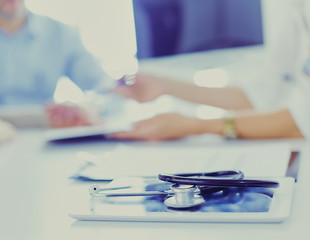 Close up of doctor and patient sitting at the desk near the window in hospital