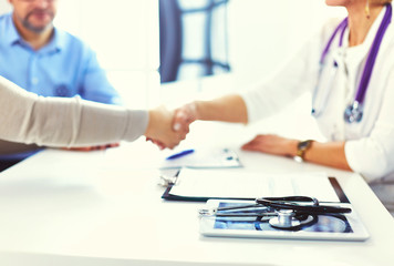 Woman doctor handshaking with a senior couple