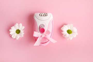 Pink epilator with flowers on pink background. Hair removal concept.