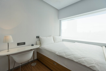 Tiny bedroom with white sheets and white pillows in the bed