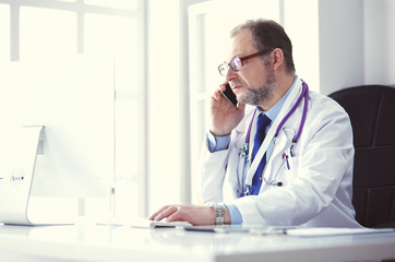 Portrait of senior doctor in office sitting at the desk