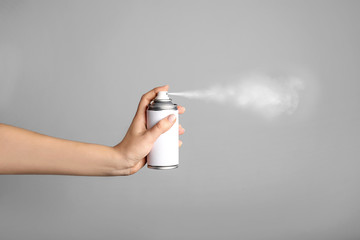 Woman holds spray can in hands on grey background - obrazy, fototapety, plakaty