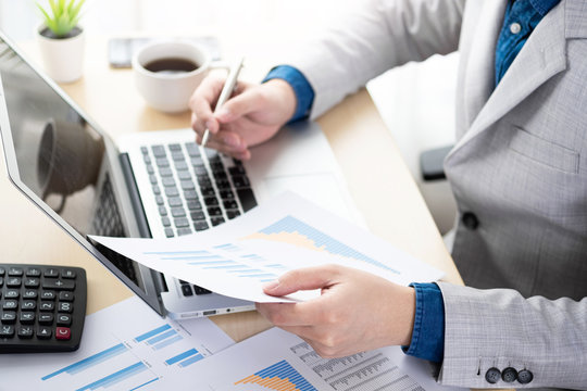 Businessman checking the business reports from the financial imformation from business document and laptop computer. Online business and economy concept.