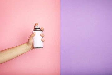 Woman holds spray can in hands on pink background