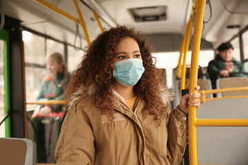 African-American woman with disposable mask on bus. Virus protection