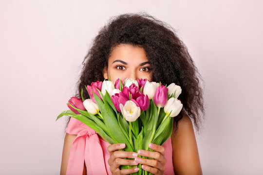 Young african woman with flowers on white background. Women's day concept