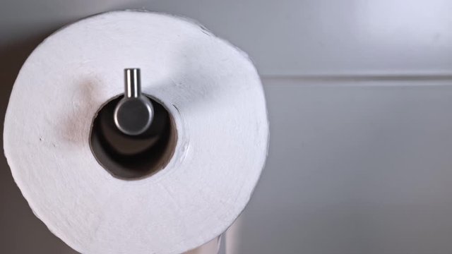 Macro view of rolling white toilet paper in a tiled bathroom with copy space available