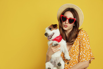 Young woman with her cute Jack Russell Terrier on yellow background, space for text. Lovely pet