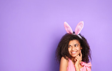 Obraz na płótnie Canvas Young african woman with rabbit ears against violet background. Easter concept