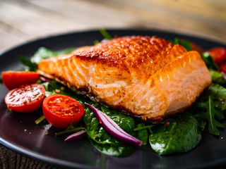 Fried salmon steak and vegetables on wooden table
