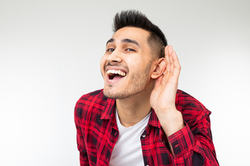 brunette man in a checkered shirt wide open eavesdrops on a conversation on a white studio background