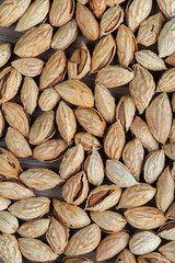 Unpeeled raw almonds in a handmade textile bag, organic and healthy food concept. Space for text, wooden table 