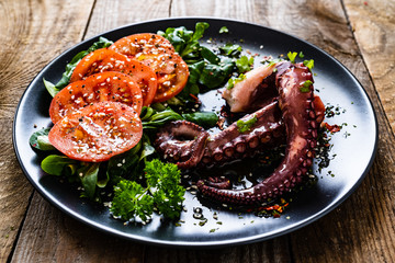 Fried octopus and vegetables on wooden table