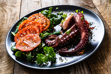Fried octopus and vegetables on wooden table