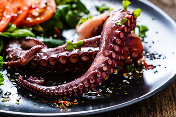 Fried octopus and vegetables on wooden table