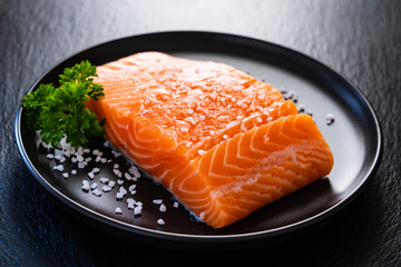 Fresh raw salmon steaks on black stone board