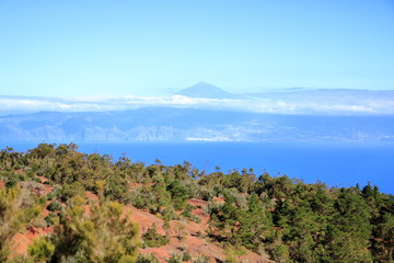 Colorful red earth and sand hills of volcanic origin above "Mirador de Abrante" in Agulo on La Gomera - looking north onto the atlantic ocean with Teide volcano on Tenerife