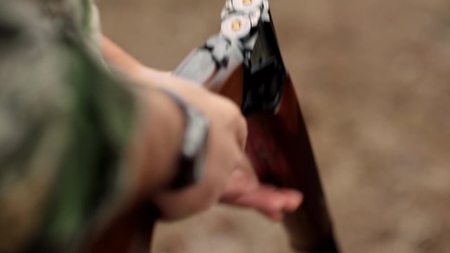 A man loads a barrel shotgun outdoors