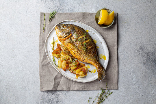 Grilled sea bream or dorada on gray plate. Gray background