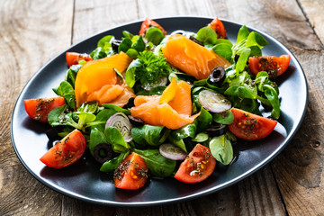 Salmon salad - smoked salmon and vegetables on wooden background