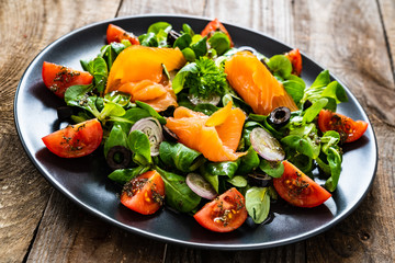 Salmon salad - smoked salmon and vegetables on wooden background
