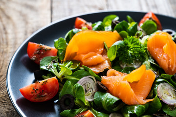 Salmon salad - smoked salmon and vegetables on wooden background