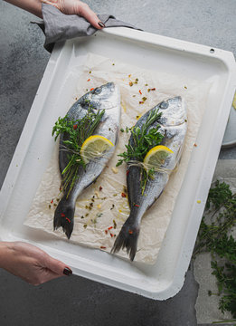 Women holding a bakind tray with dorada or bream