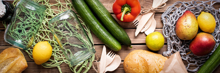 Concept of zero waste, environmental friendly products with glass jars and net bags on wooden background.