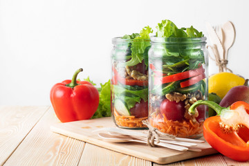 Healthy homemade mason jar salad with fresh pear tomatoes, carrots and herbs. Vegetarian concept.