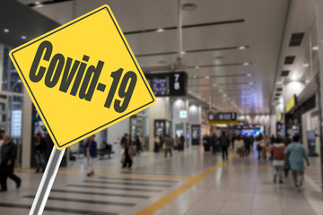 Crowd of people at airport with Covid-19 Sign
